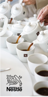 Multiple white teapots pouring coffee into teacups with the Nestle logo overlayed.